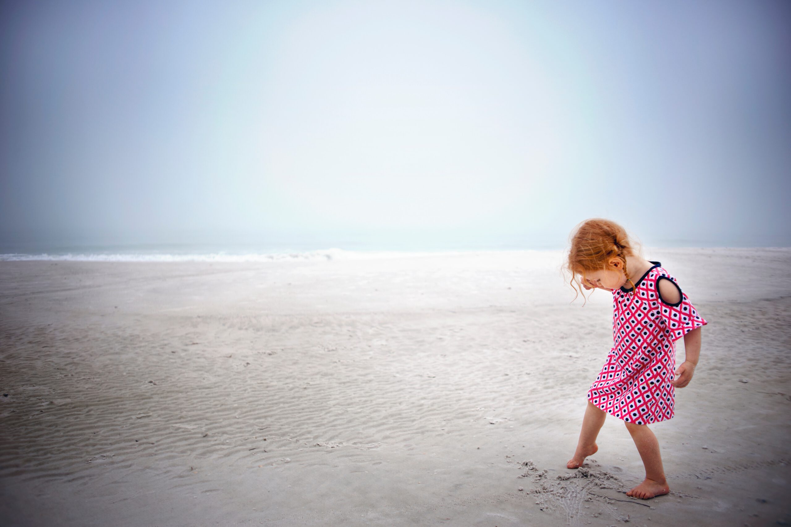 girl-playing-on-sand-near-the-ocean-during-day-time-2524143